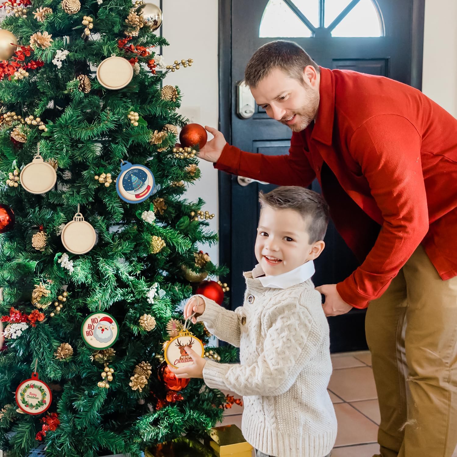 Man and child decorating a Christmas tree with ornaments.