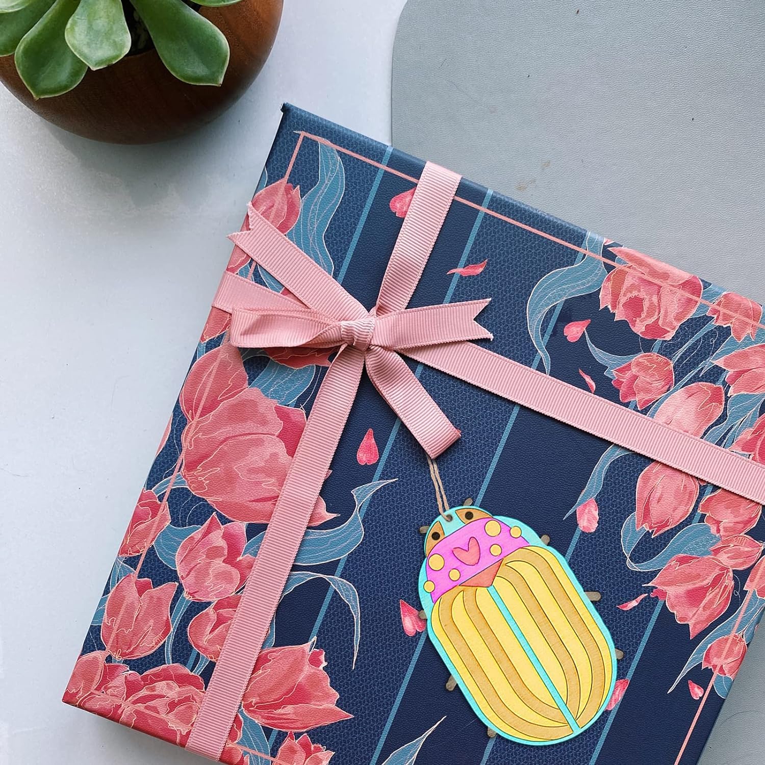 Gift box with floral design and pink ribbon on a white surface