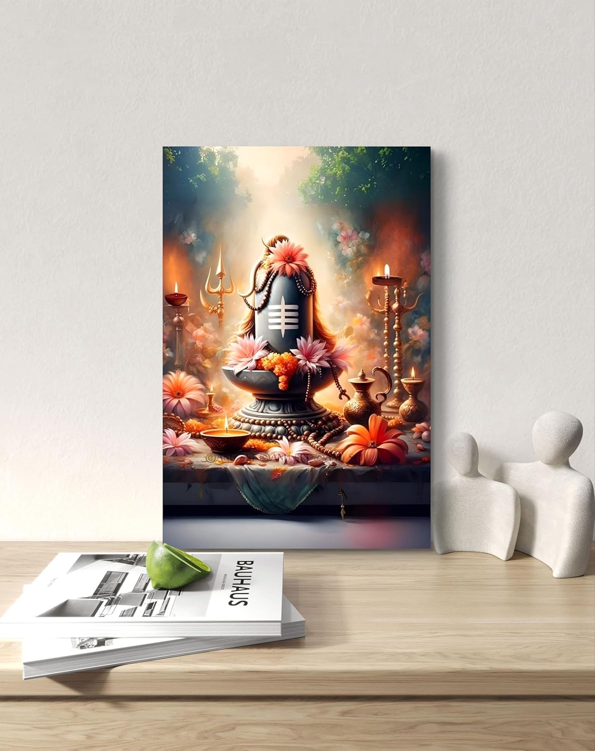 Framed artwork of a religious statue with flowers and candles on a wooden table.
