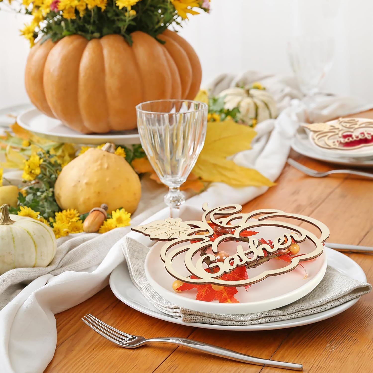 Thanksgiving table setting with pumpkins, flowers, and a decorative 'Gather' sign.