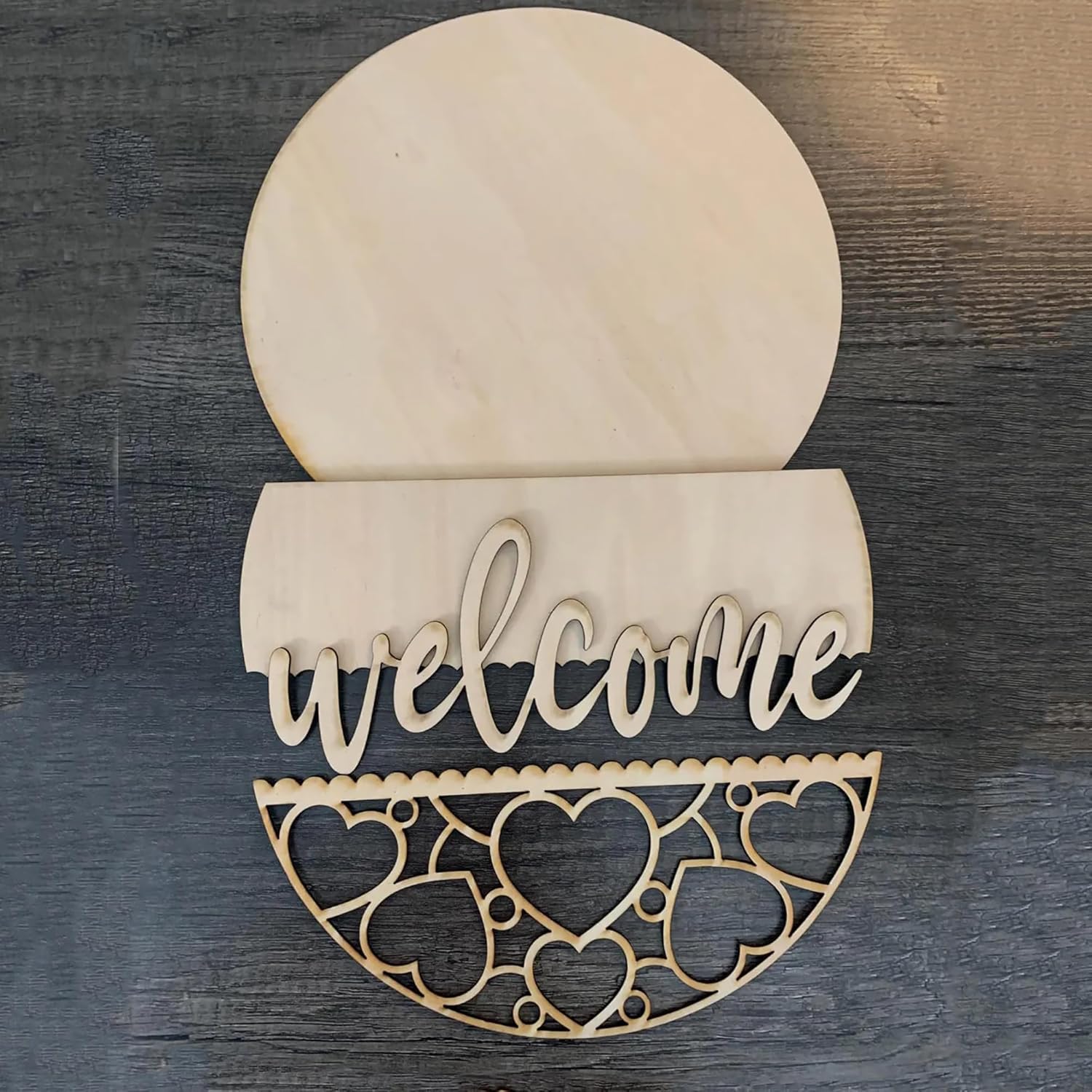 Wooden decorative sign with 'welcome' text and heart patterns on a wooden background