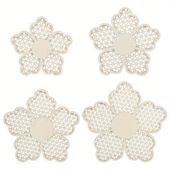 Four white flower-shaped coasters with intricate patterns on a white background