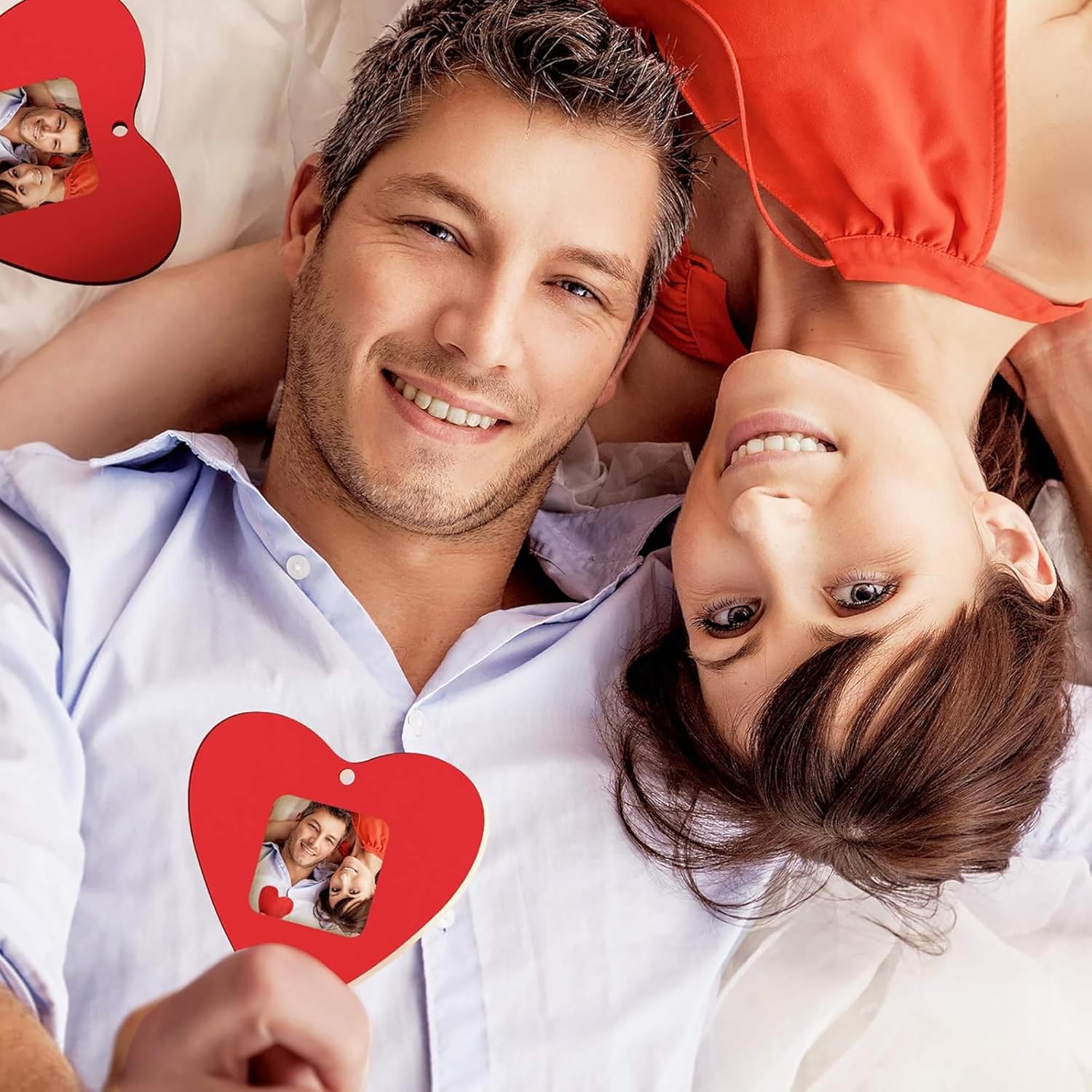Couple lying down together with a red heart-shaped photo frame