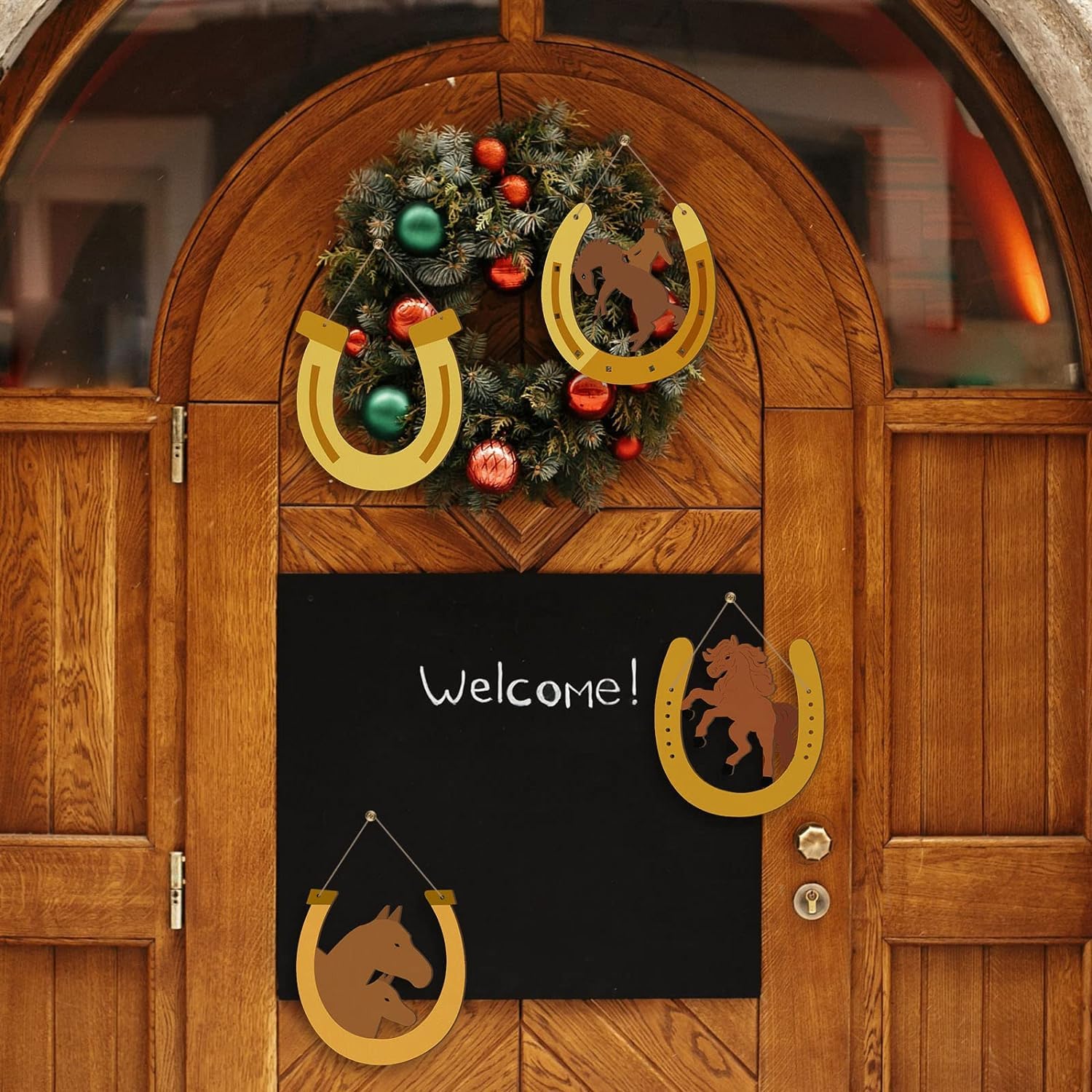 Wooden door with festive wreath and decorations, including horseshoes and a 'Welcome!' sign.