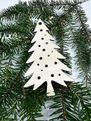 White Christmas tree ornament with black dots on a green pine branch
