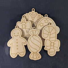 Wooden Christmas ornaments shaped like gingerbread man, candy, and bow on a dark background