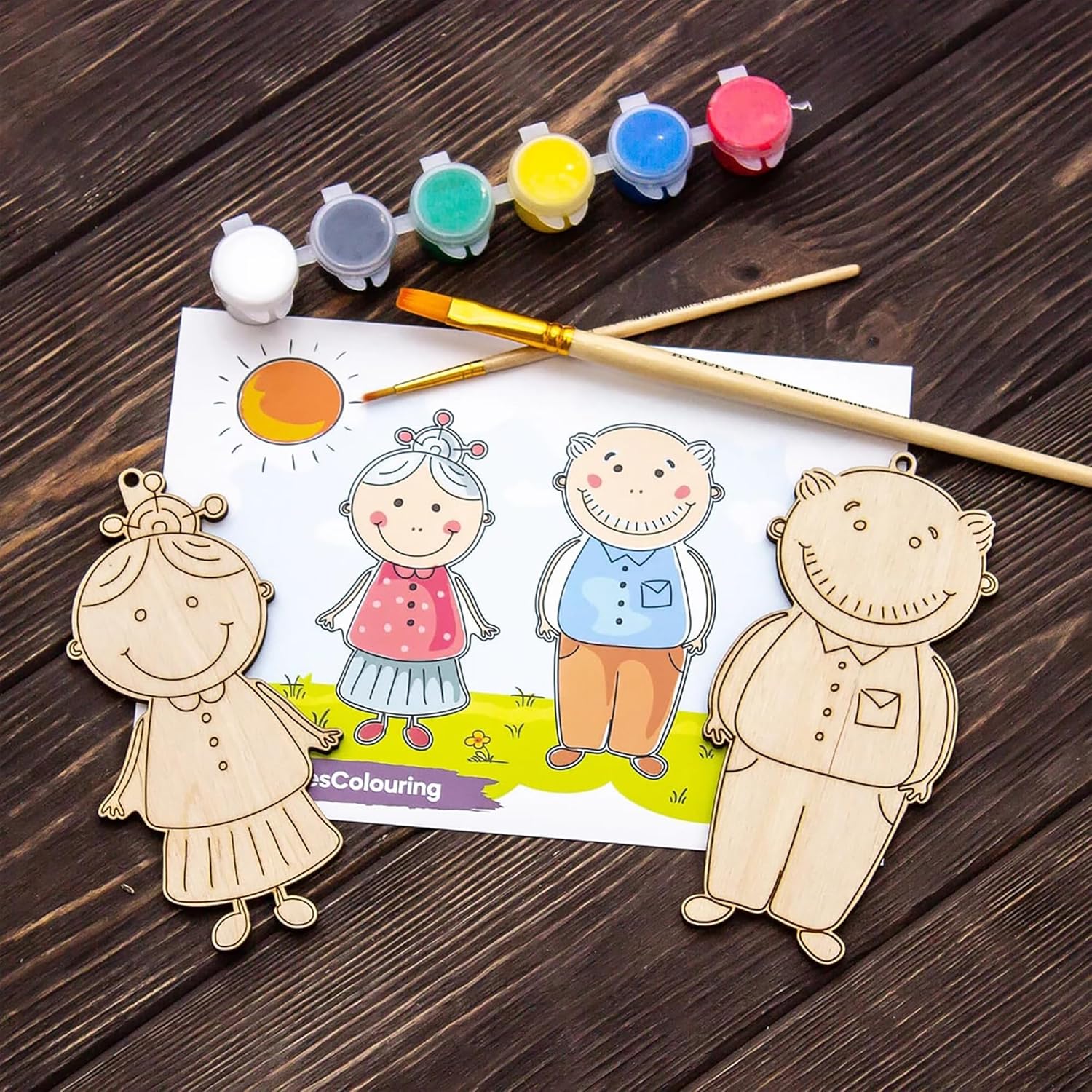 Wooden cutouts of cartoon characters on a coloring sheet with paint and brushes on a wooden surface
