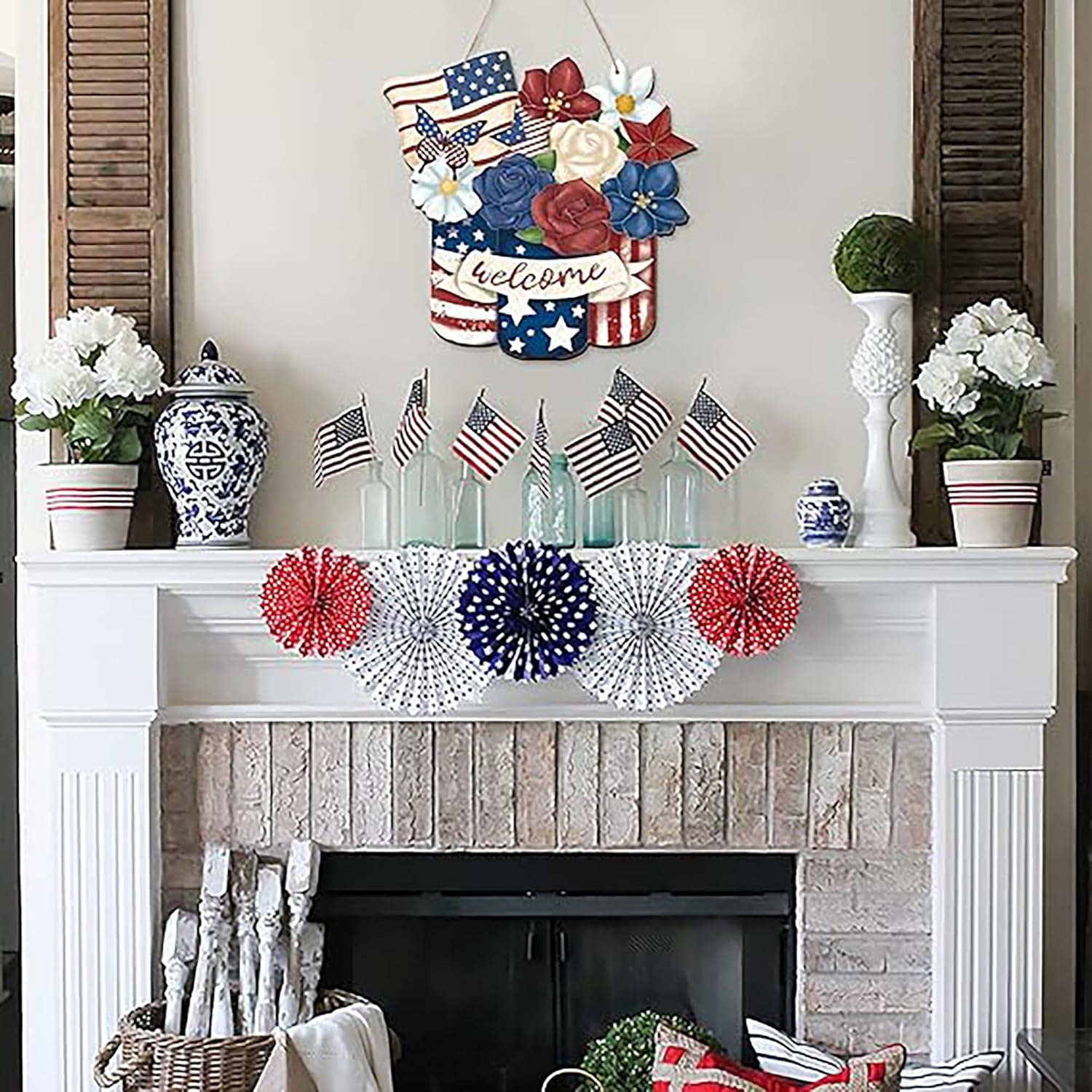Decorative fireplace mantel with patriotic elements including American flags, flowers, and a 'welcome' sign.