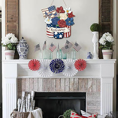 Decorative fireplace mantel with patriotic elements including American flags, flowers, and a 'welcome' sign.