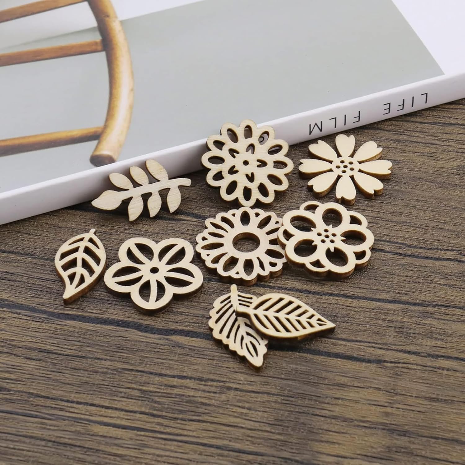 Wooden floral and leaf-shaped earrings on a wooden surface with a magazine in the background.
