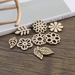 Wooden floral and leaf-shaped earrings on a wooden surface with a magazine in the background.