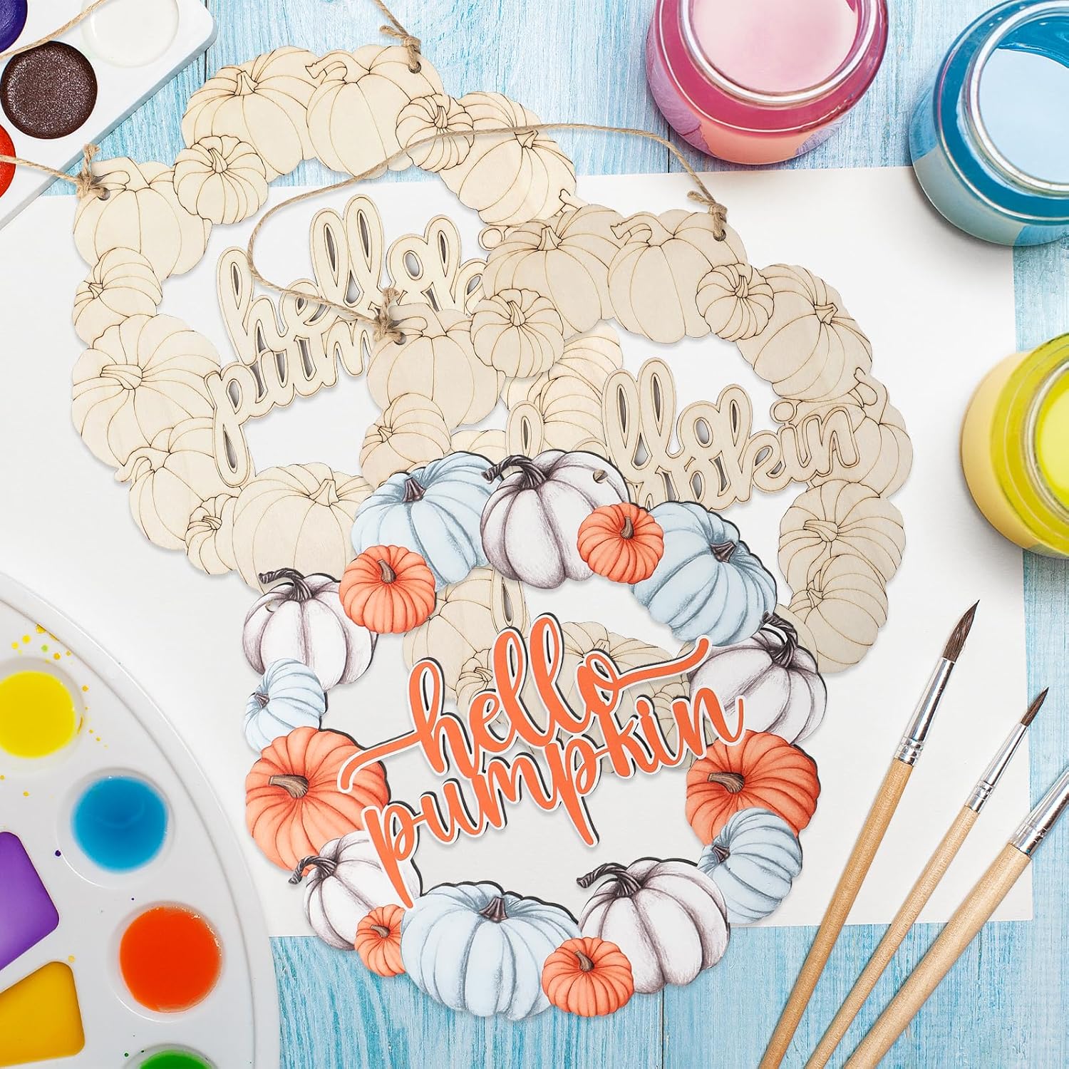 Decorative wreath with 'Hello Autumn, Hello Pumpkin' text on a table with art supplies.