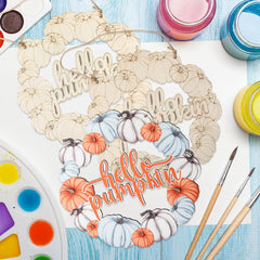 Decorative wreath with 'Hello Autumn, Hello Pumpkin' text on a table with art supplies.