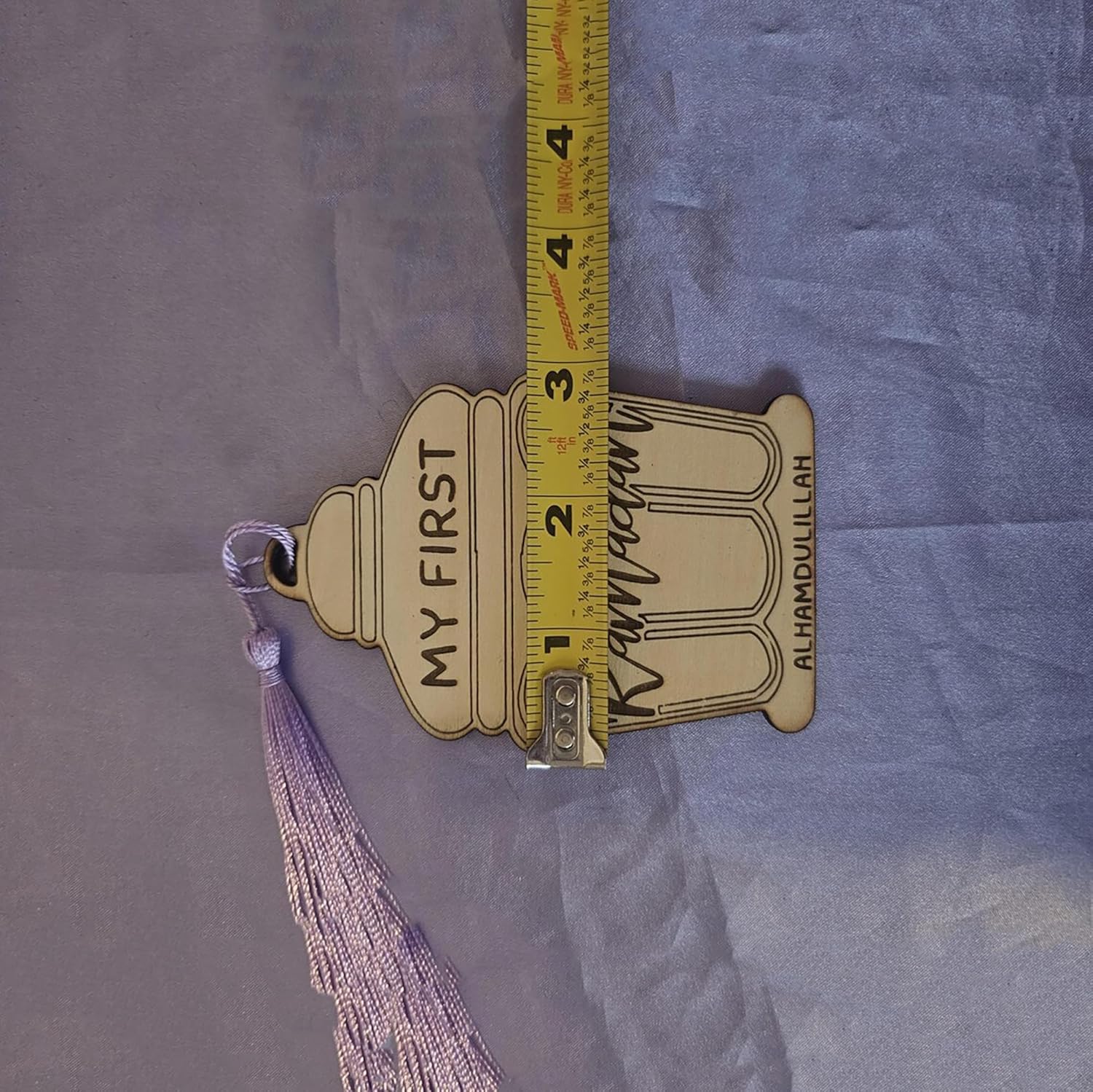 Measurement of a decorative item with 'My First' and 'Alhamdulillah' text on a purple fabric background.