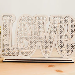 Wooden decorative sign with 'LOVE' pattern on a wooden surface