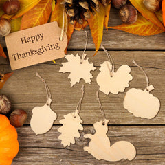 Decorative tags shaped like leaves, pumpkins, and a squirrel on a wooden surface with a 'Happy Thanksgiving' tag.