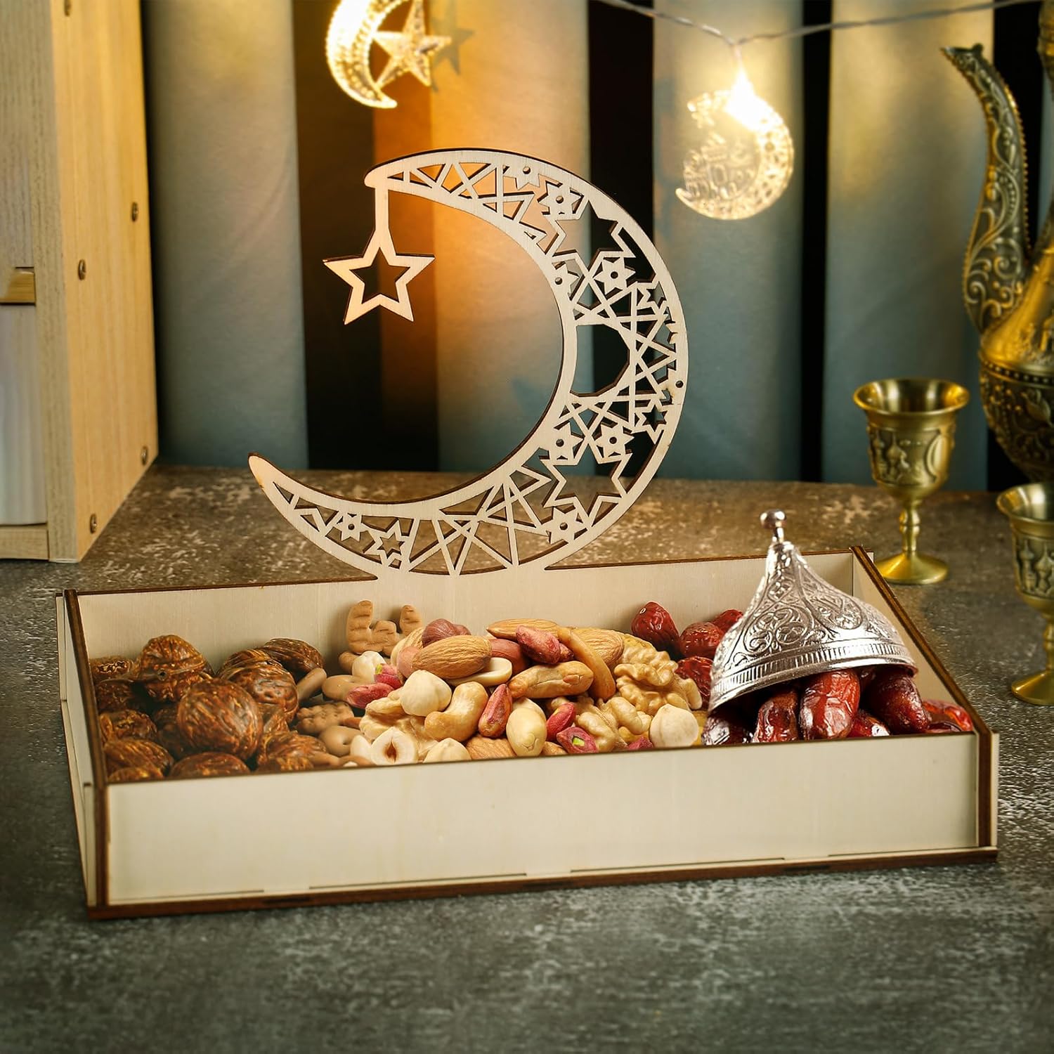Decorative box with a crescent moon and star design, filled with nuts and dried fruits, on a dark surface.
