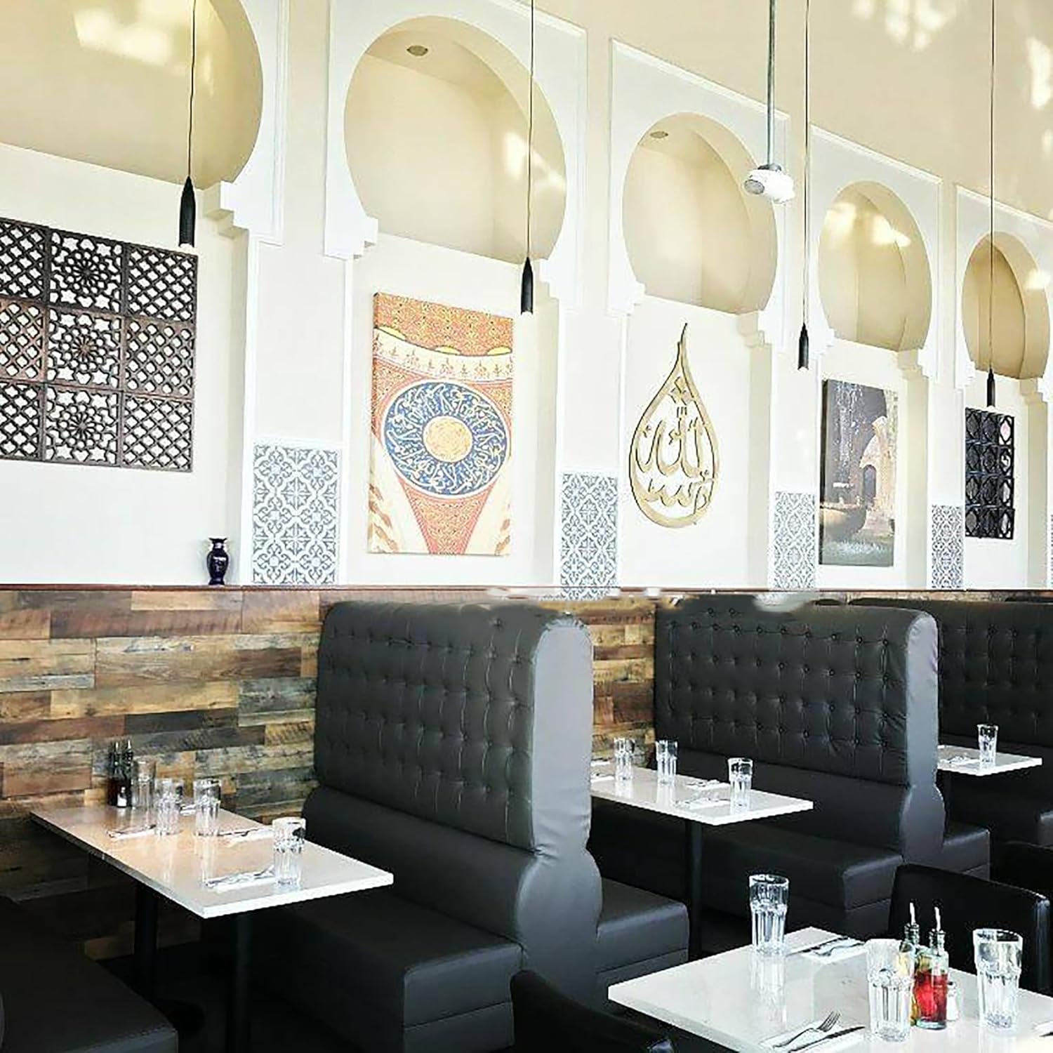 Modern restaurant interior with black leather booths, tables, and decorative wall art.