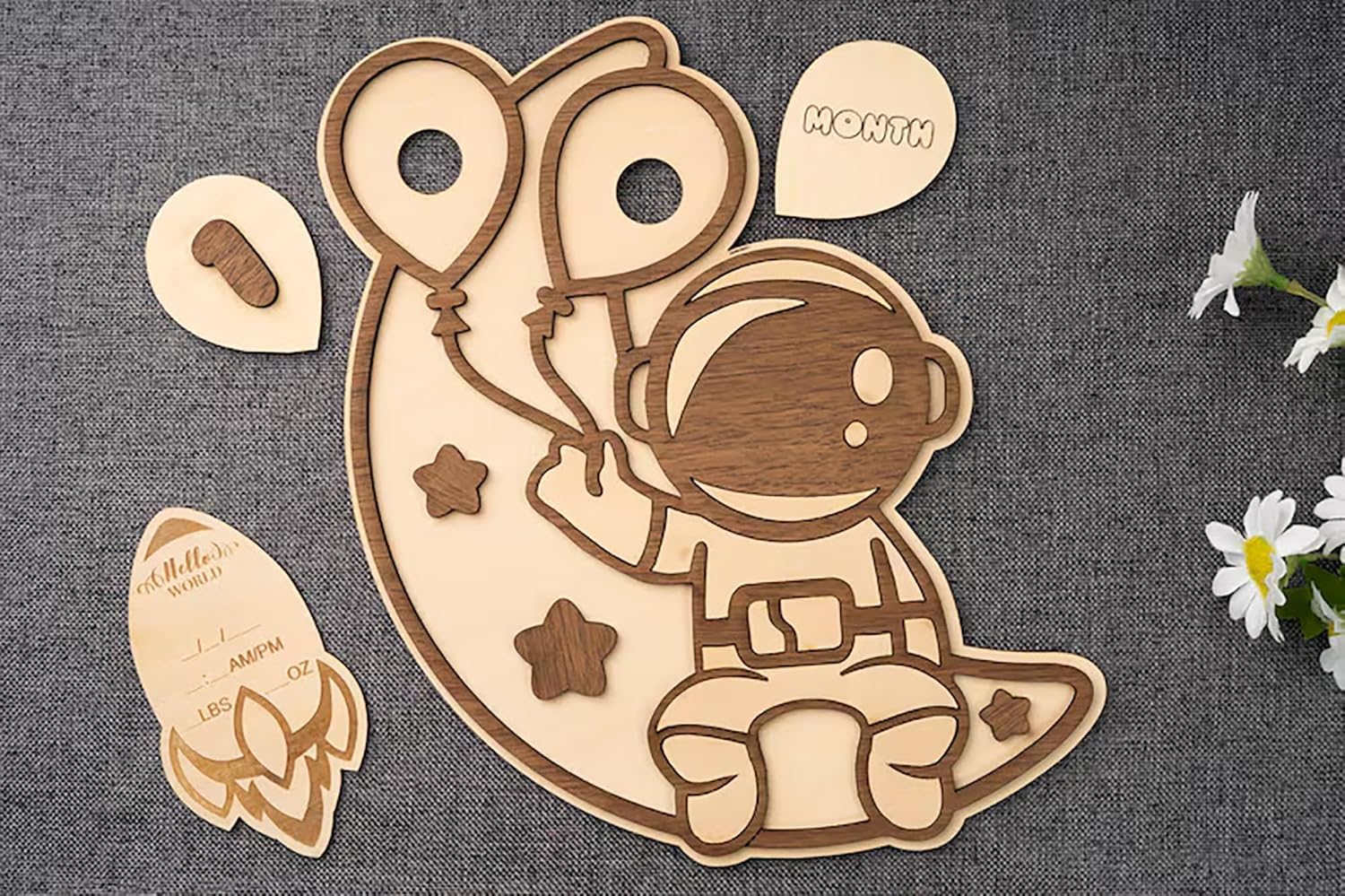 Wooden baby milestone plaque with astronaut design on a textured surface.