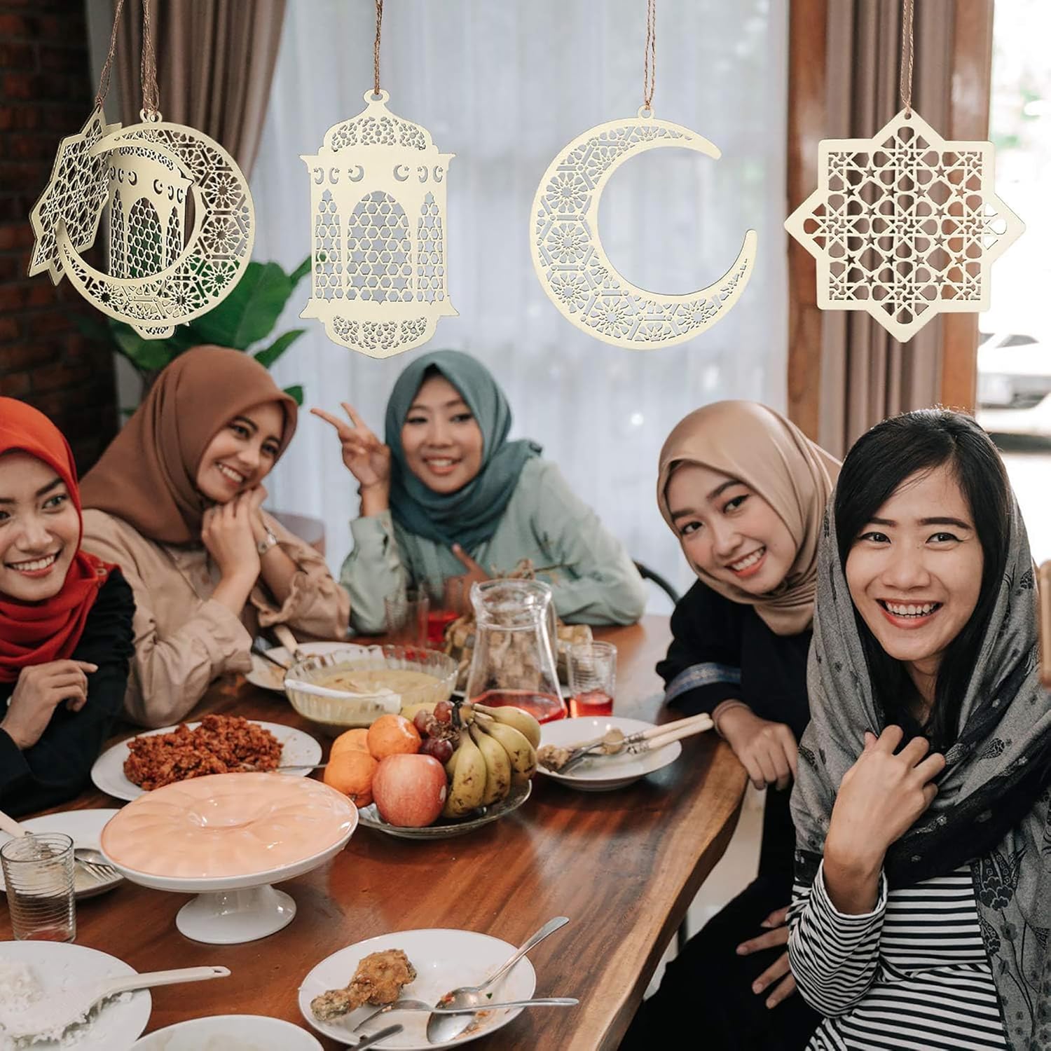 Group of women enjoying a meal together with decorative lanterns above.