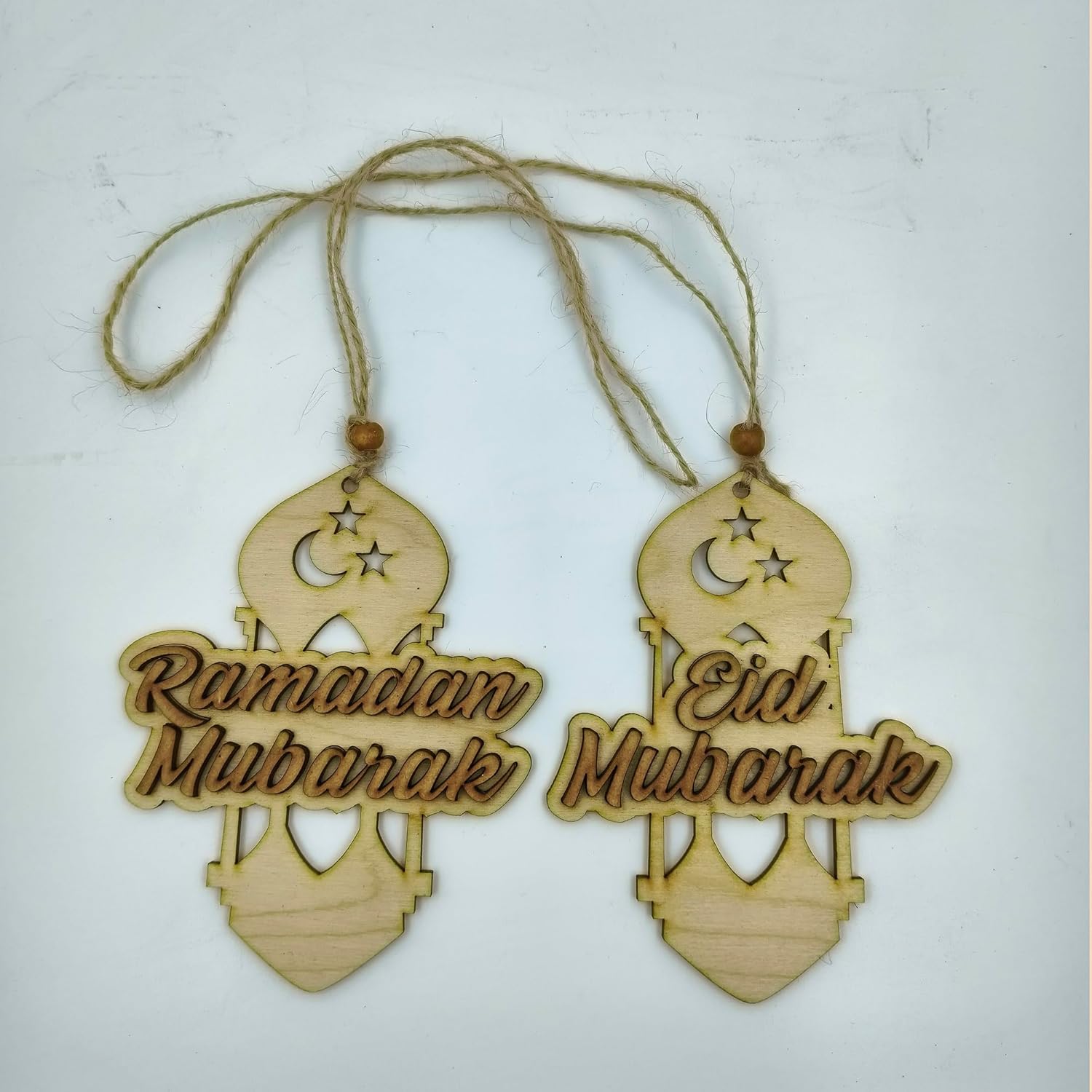 Two wooden hanging decorations with 'Ramadan Mubarak' and 'Eid Mubarak' text on a light background.