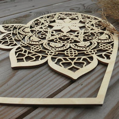 Wooden decorative panel with intricate cut-out patterns on a wooden surface