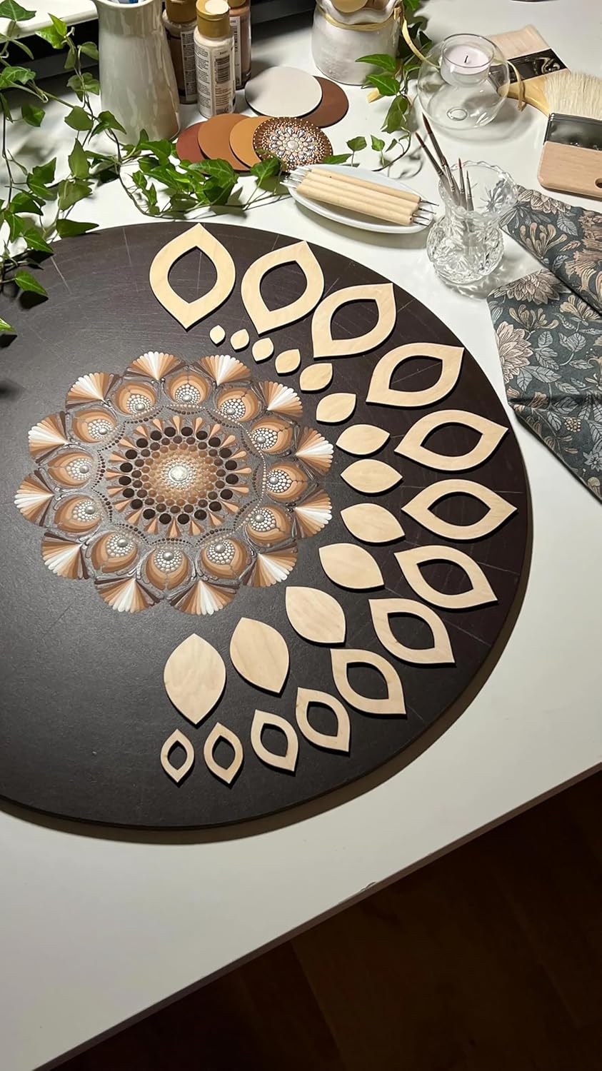 Decorative wooden cutout with intricate design on a black board, surrounded by greenery and other decorative items.