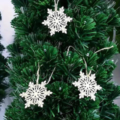 Green artificial Christmas tree with white snowflake ornaments.