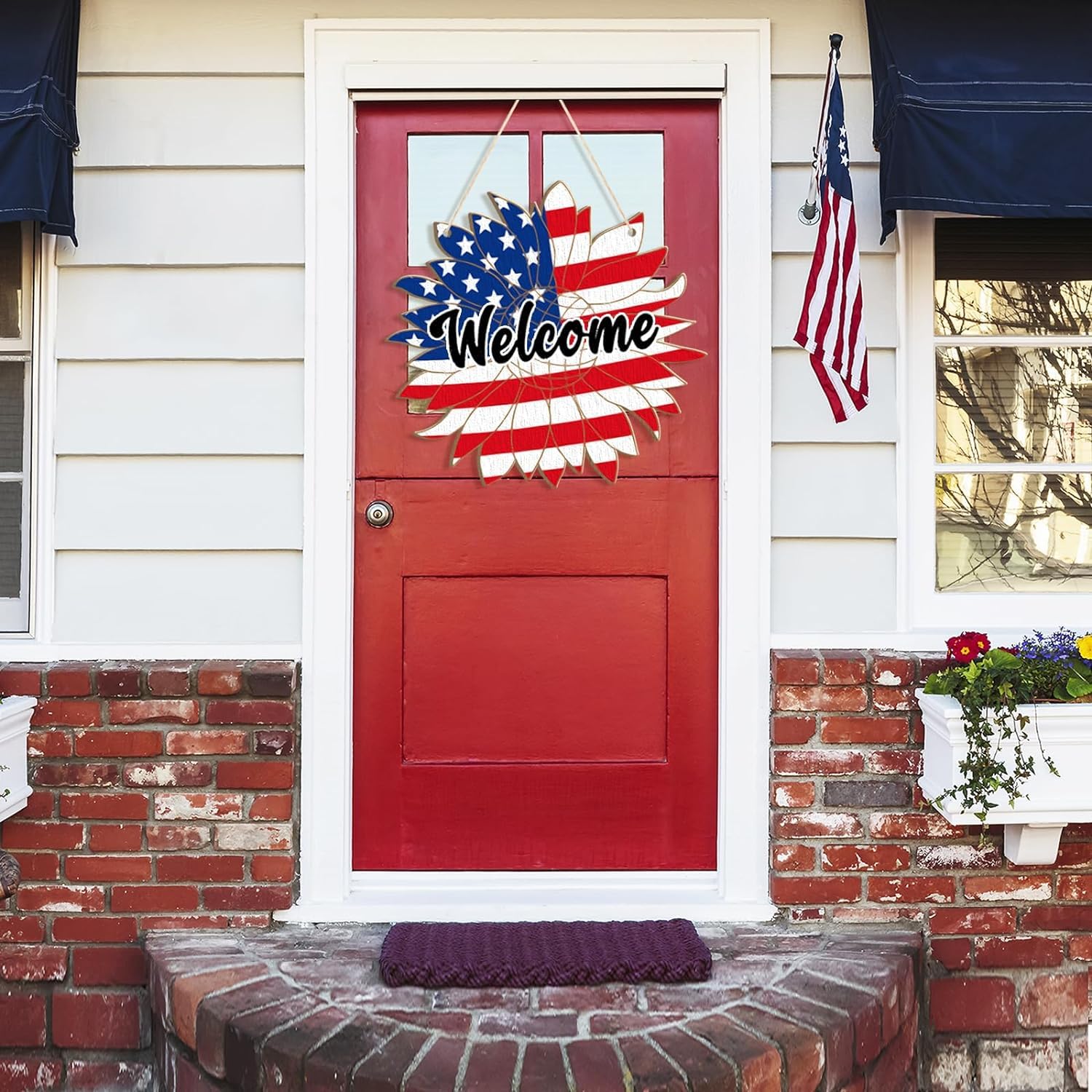 Red door with 'Welcome' sign featuring American flag design, American flag on right side, and flowers on left.