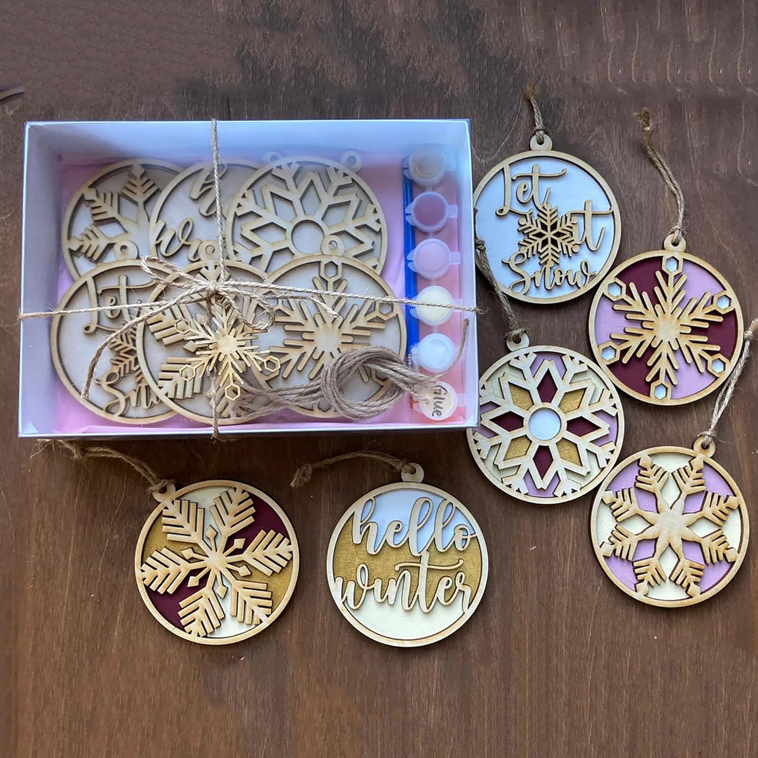 Decorative Christmas ornaments with snowflake designs and 'hello winter' text on a wooden surface.