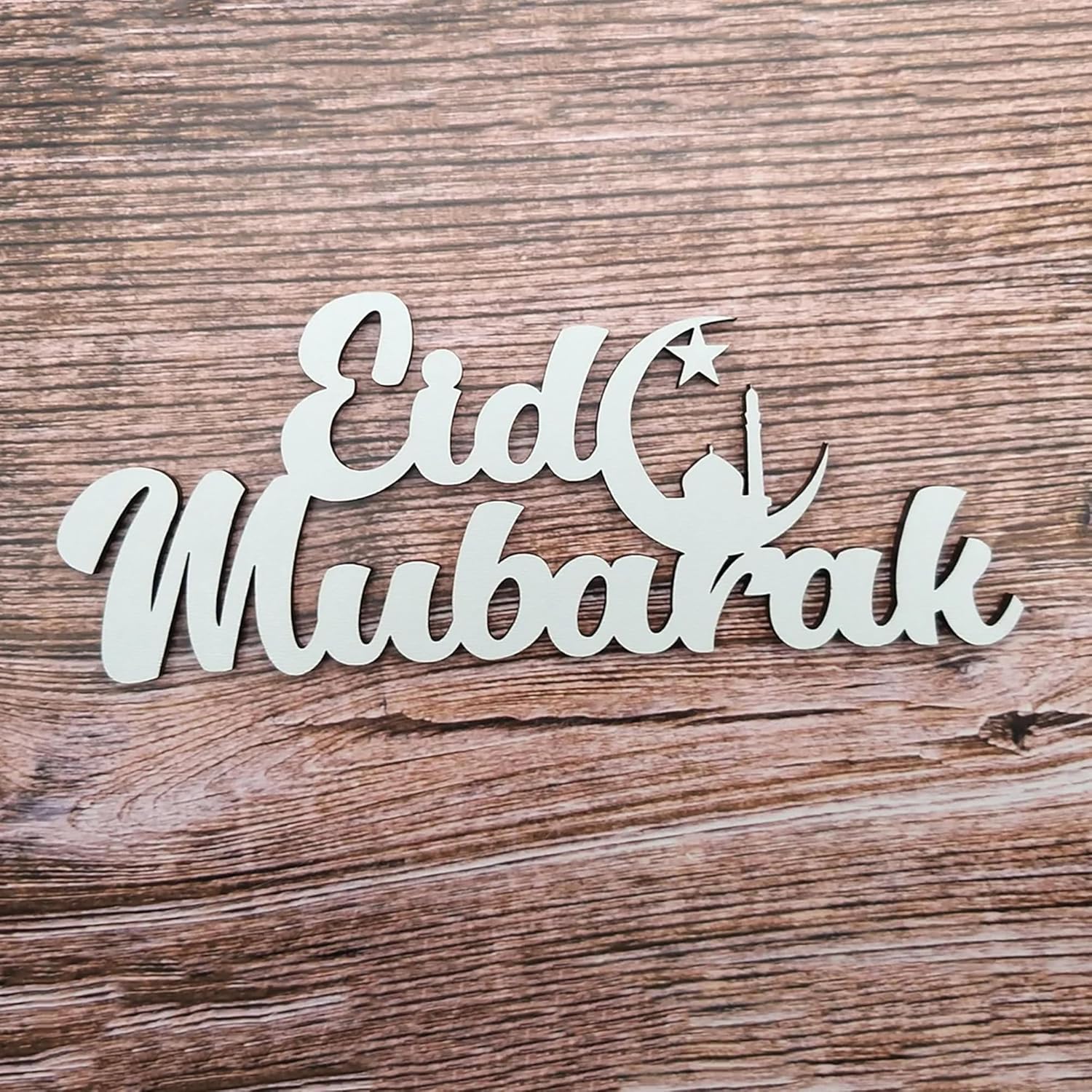 Metallic 'Eid Mubarak' sign on a wooden surface