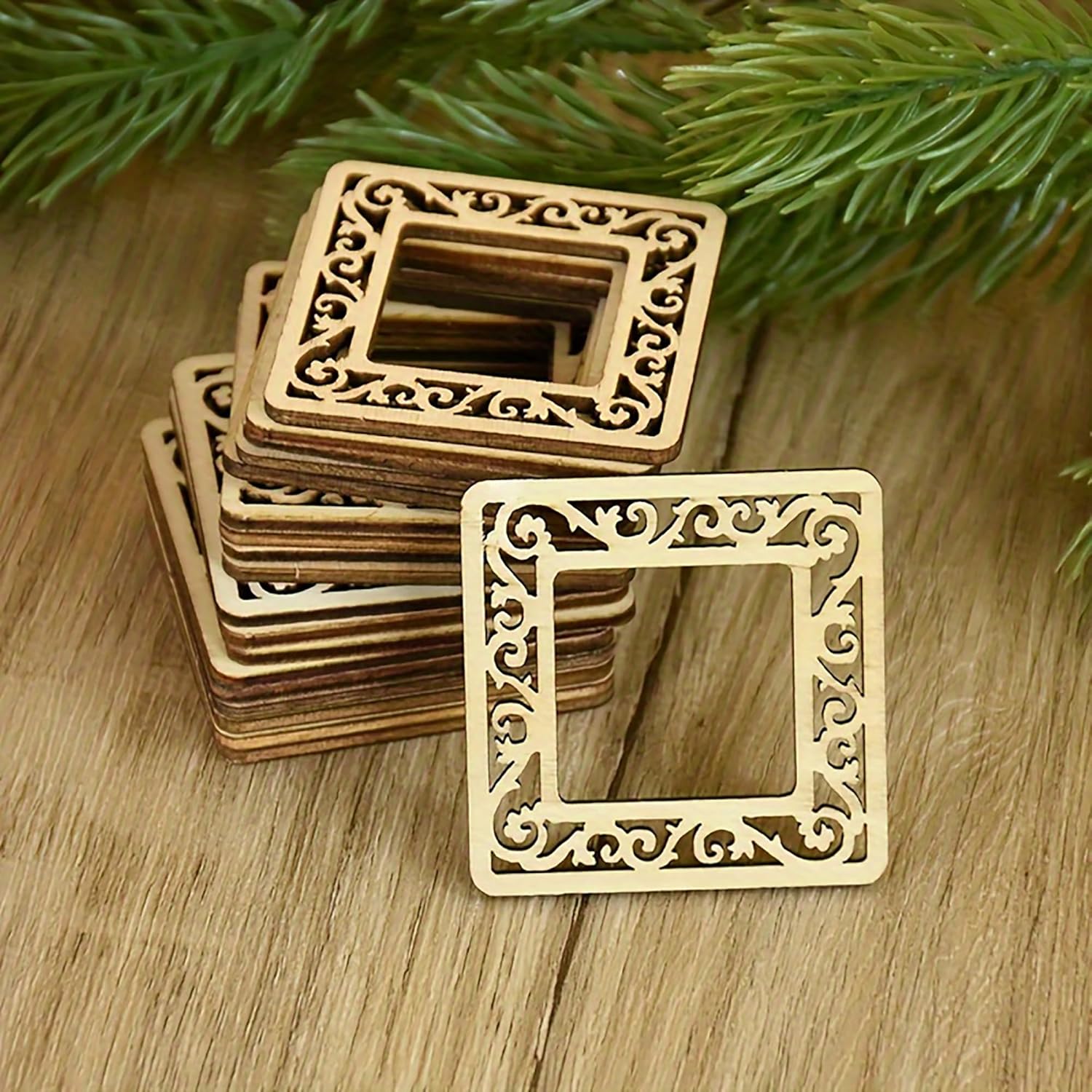 Decorative square frames with intricate patterns on a wooden surface with greenery in the background.