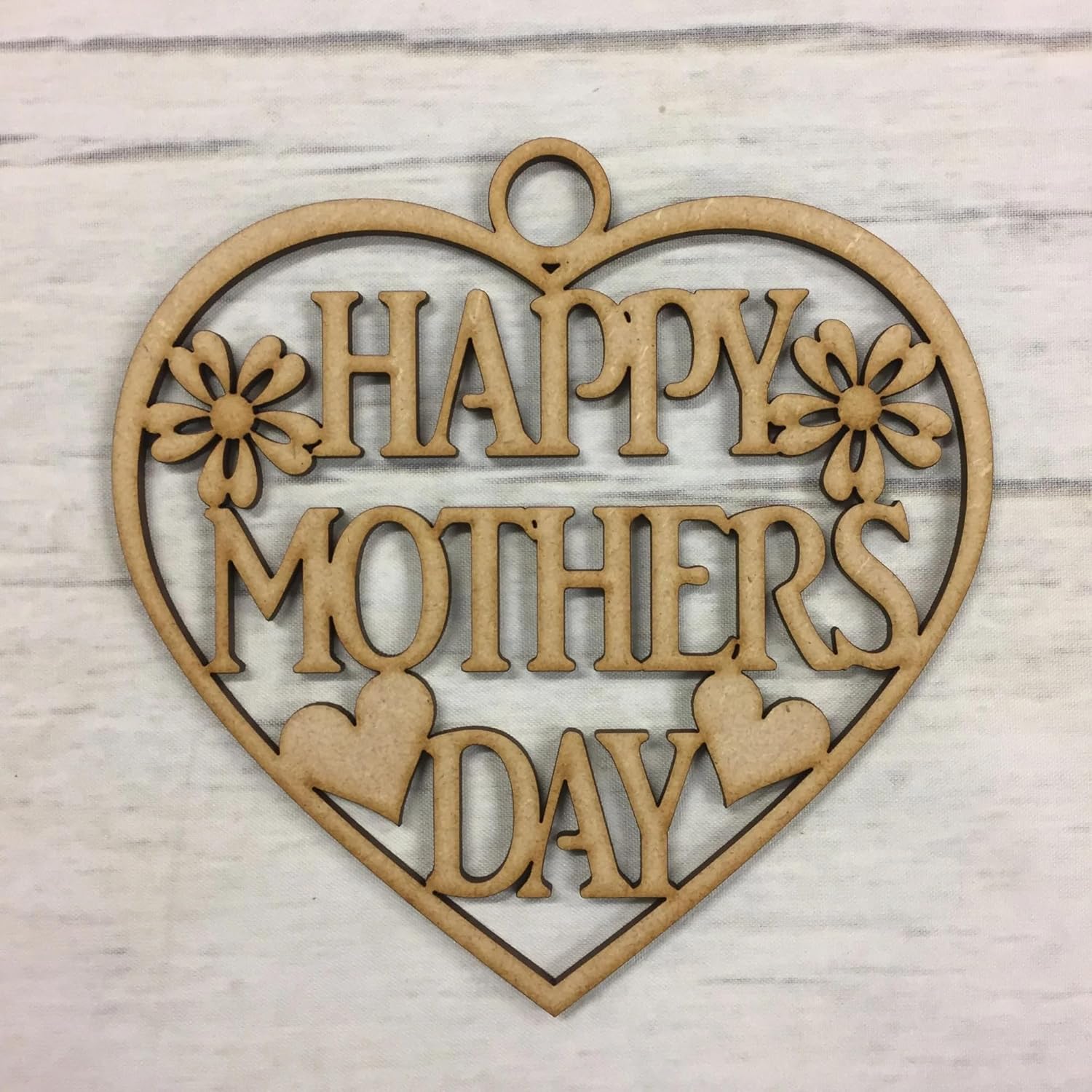Heart-shaped wooden cutout with 'Happy Mother's Day' text on a light wood background