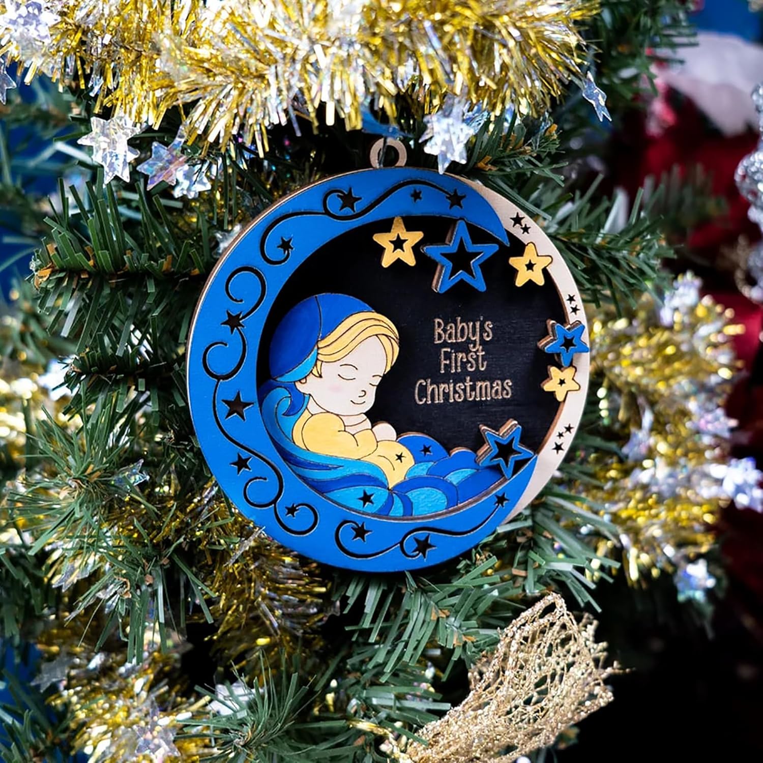 Decorative ornament for a baby's first Christmas on a decorated tree.