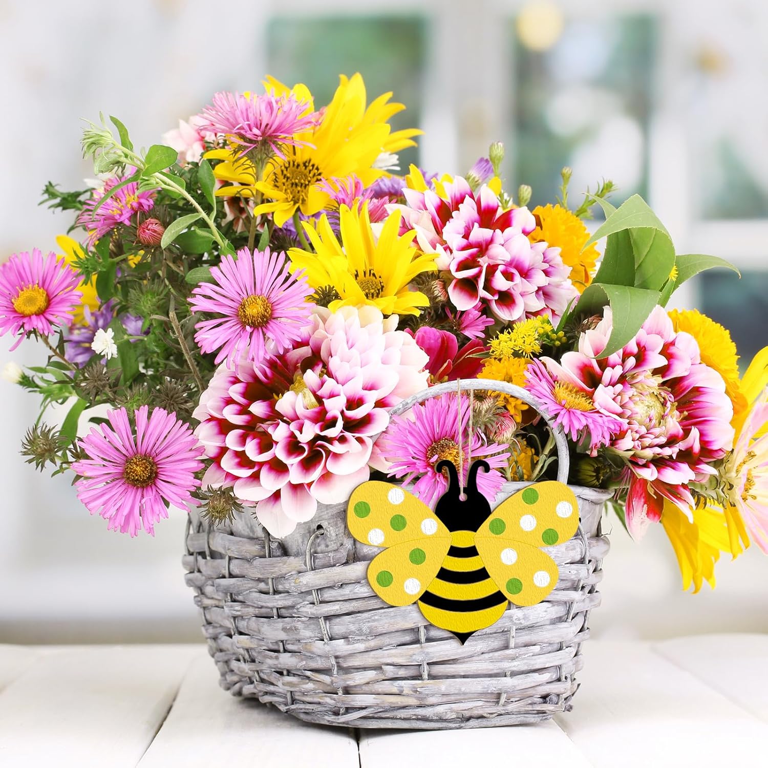 Basket of colorful flowers with a bee-shaped card on a blurred background