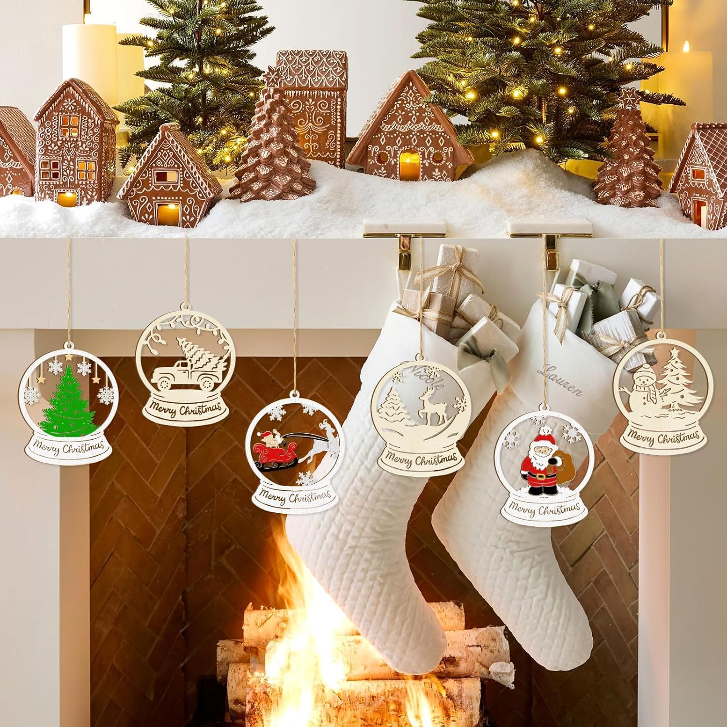 Decorative Christmas ornaments hanging over a fireplace with gingerbread houses and trees in the background.
