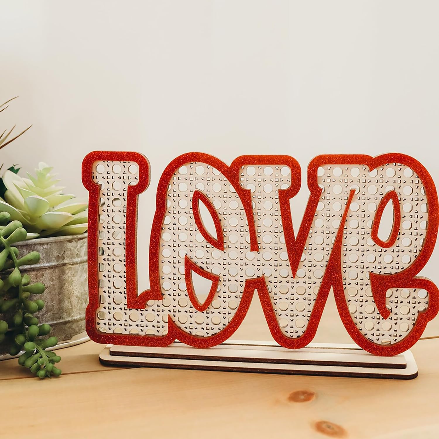 Decorative sign with 'LOVE' on a wooden surface with plants in the background