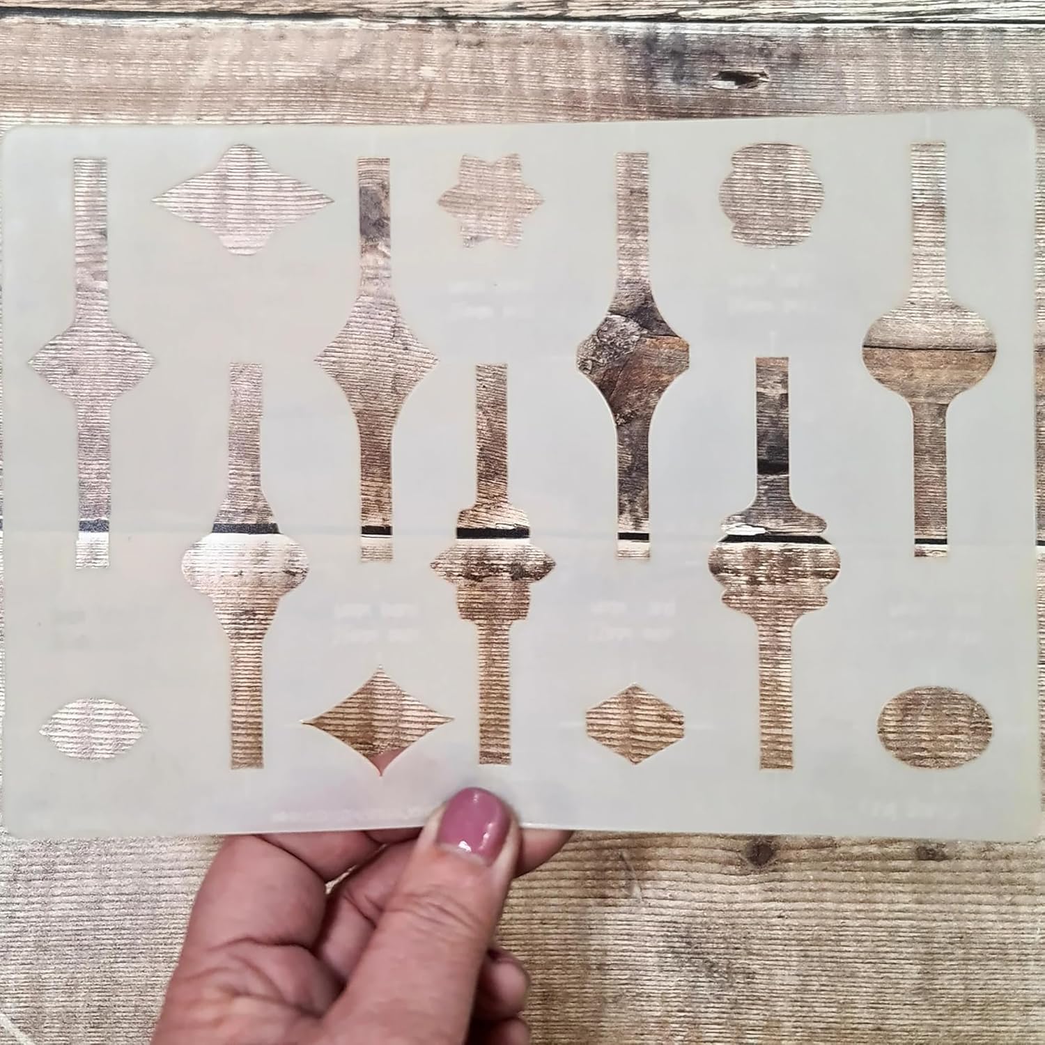Decorative stencil with geometric patterns held by a hand on a wooden surface