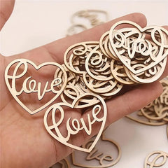 Wooden heart-shaped 'love' decorations held in a hand with more decorations on a light background.