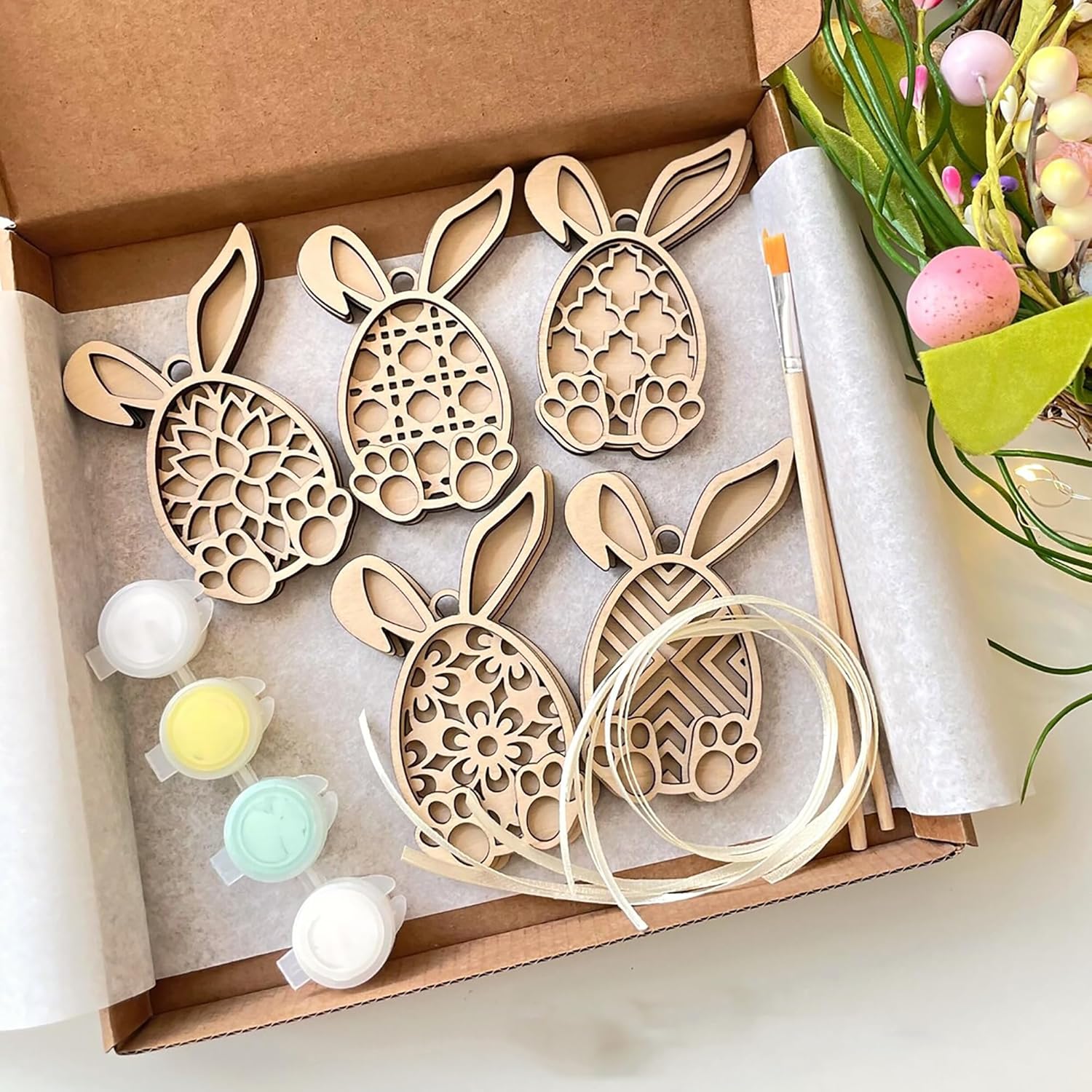 Wooden bunny shapes with paint and brush in a box, Easter-themed.