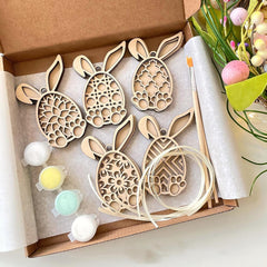 Wooden bunny shapes with paint and brush in a box, Easter-themed.