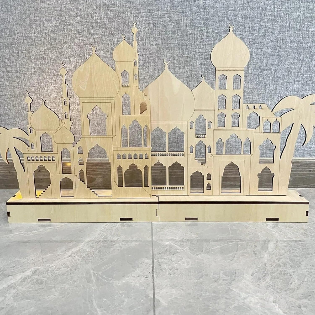 Wooden architectural model of a mosque on a gray surface with a textured wall background