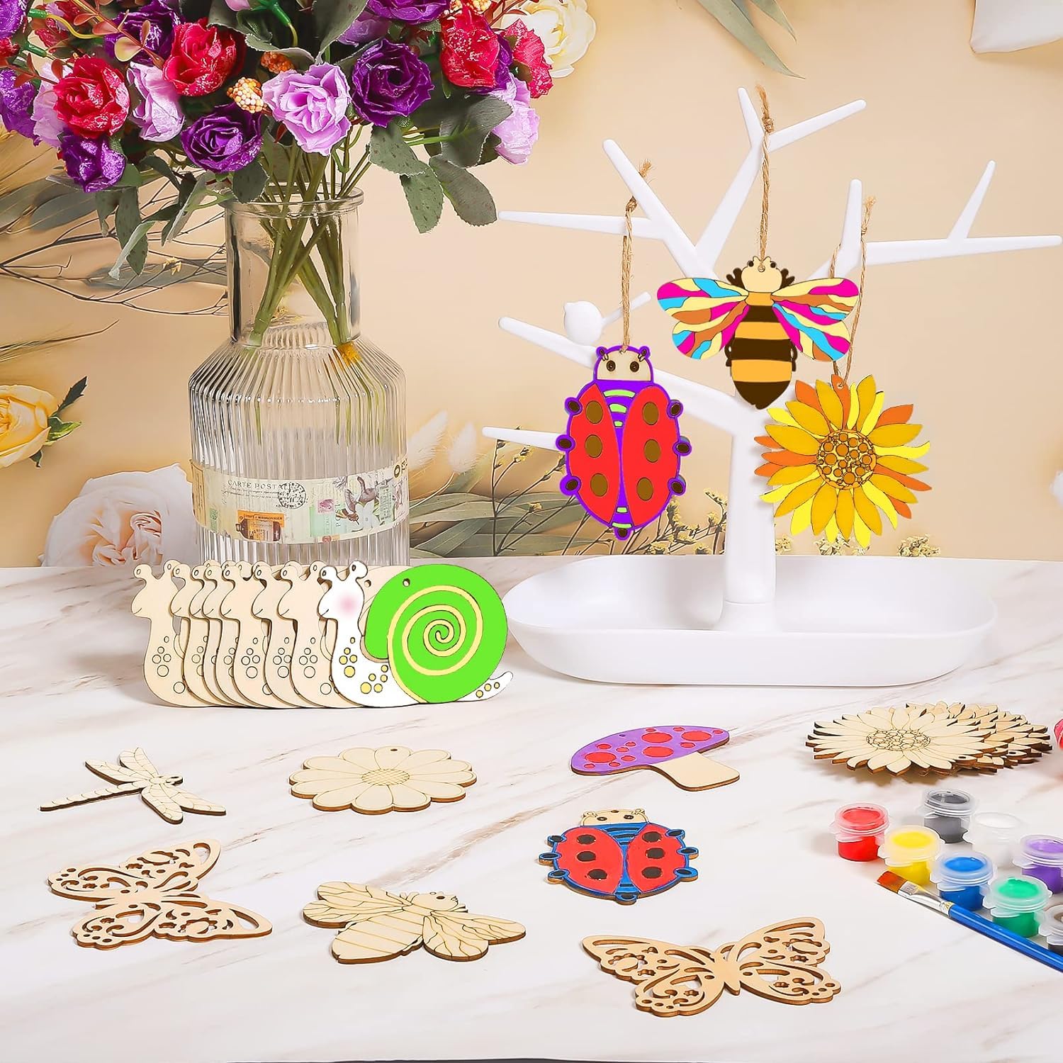 Wooden craft items including ladybugs, flowers, and butterflies on a table with a vase of flowers in the background.