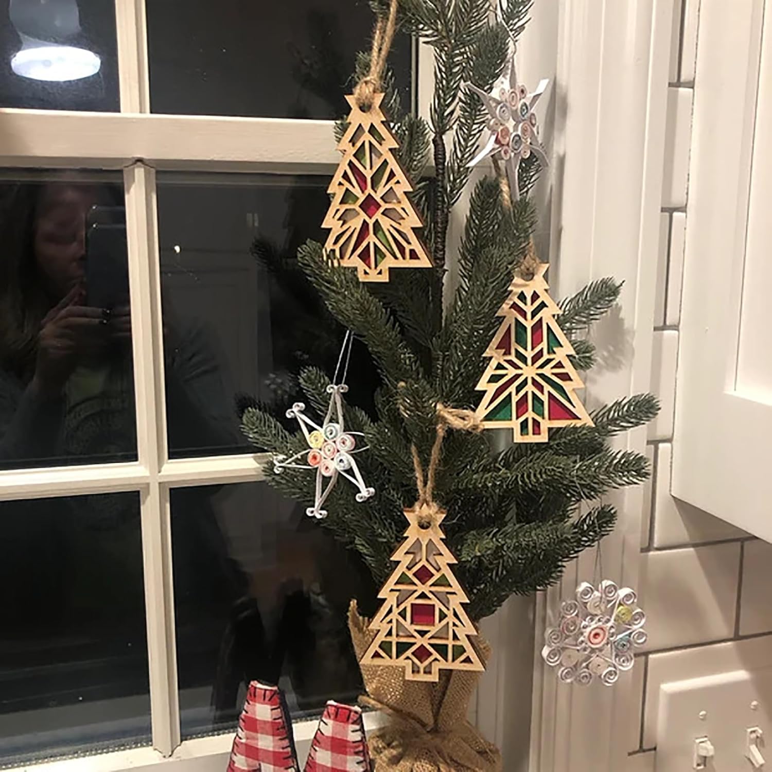 Decorative Christmas tree with geometric wooden ornaments and snowflake decorations in front of a window.