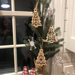 Decorative Christmas tree with geometric wooden ornaments and snowflake decorations in front of a window.