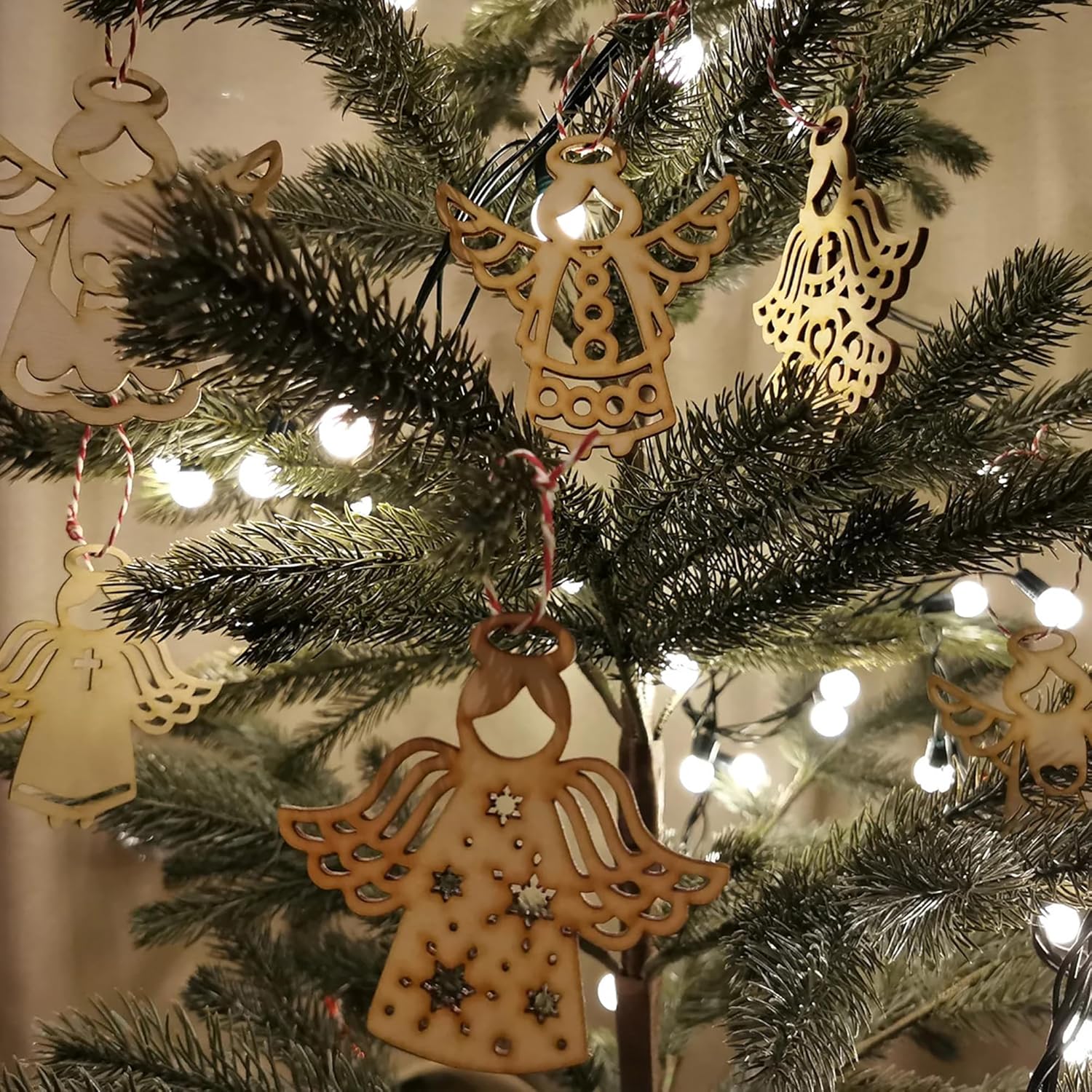 Wooden angel ornaments on a decorated Christmas tree with lights.