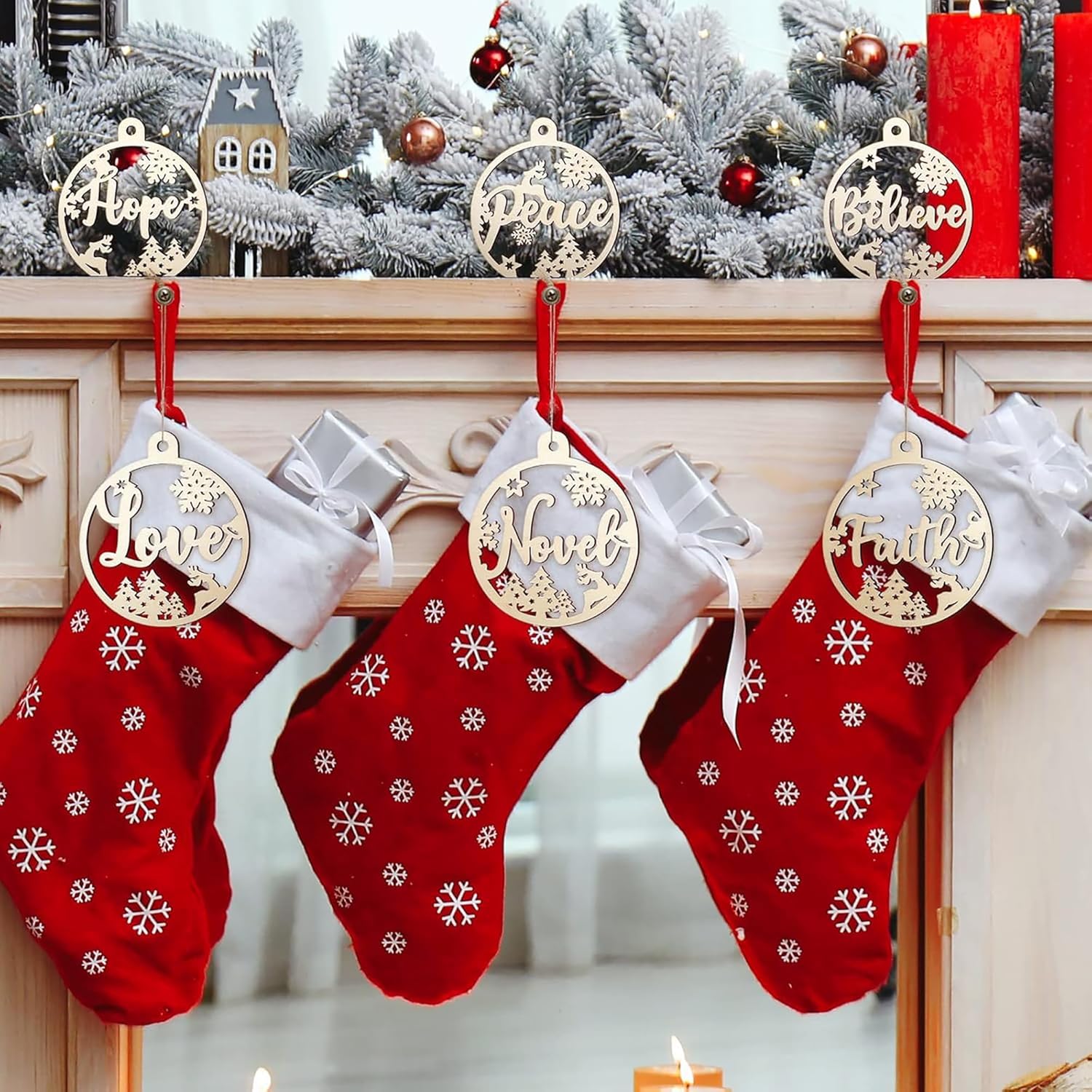 Red Christmas stockings with gold ornaments on a fireplace mantle decorated with a snowy scene.