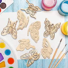 Wooden butterfly shapes on a white paper with paint containers and brushes on a blue wooden surface.