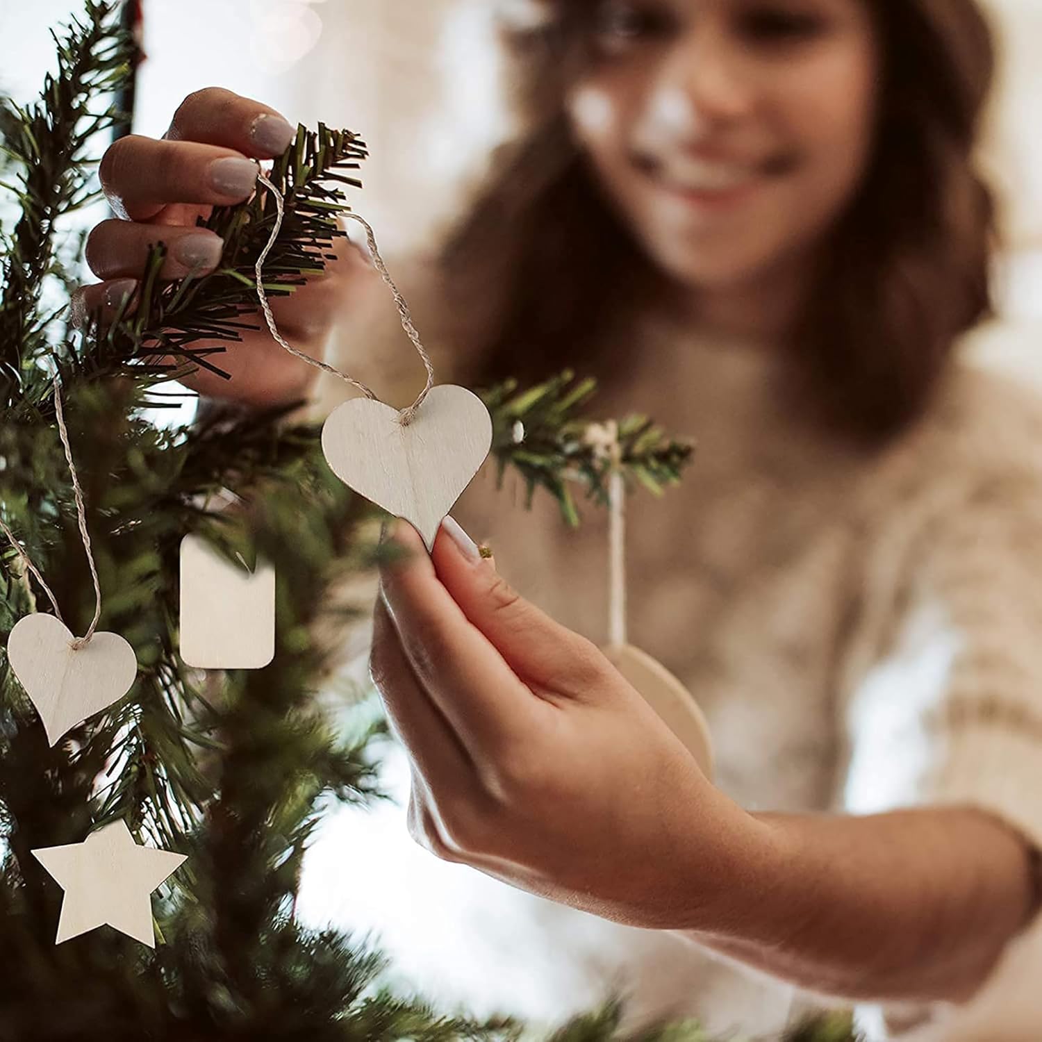 Person decorating a Christmas tree with heart-shaped ornaments