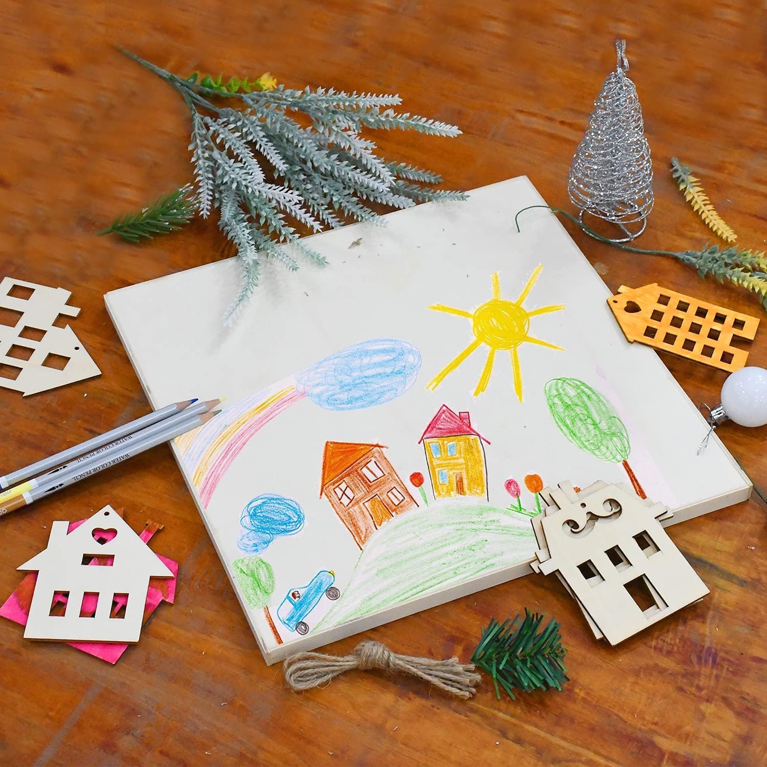 Children's drawing of a house, sun, and trees on a wooden surface with decorative items.